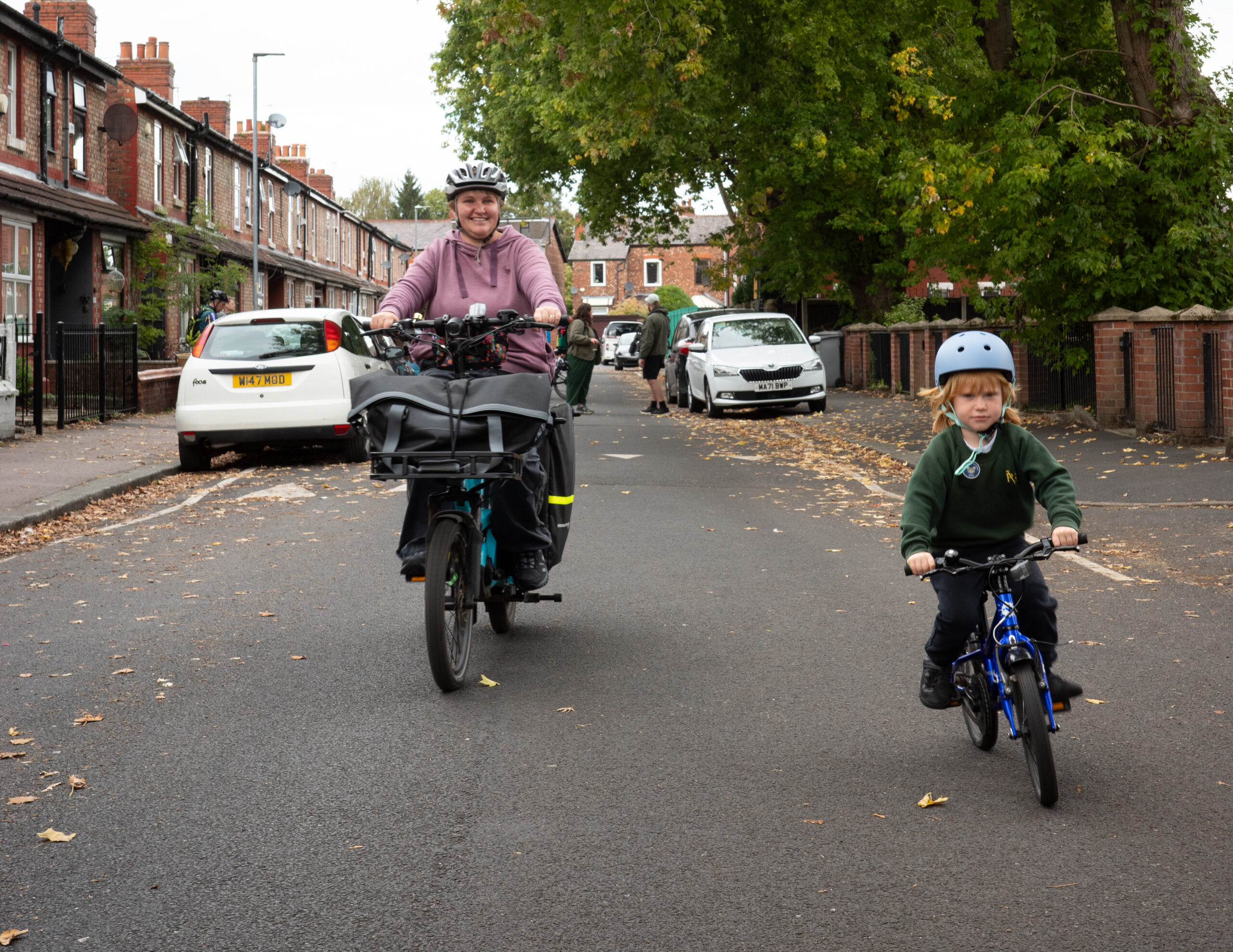 A photograph of a mother and child cycling together down a School Street in Stretford. 